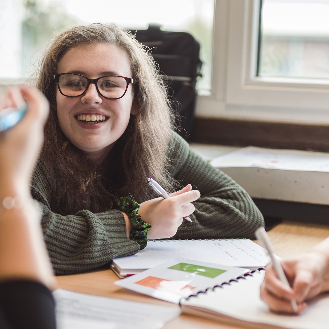 A student working at a desk with classmates